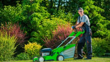 Smiling Professional Gardener with His Gasoline Lawn Mower. Professional Summer Landscaping Works